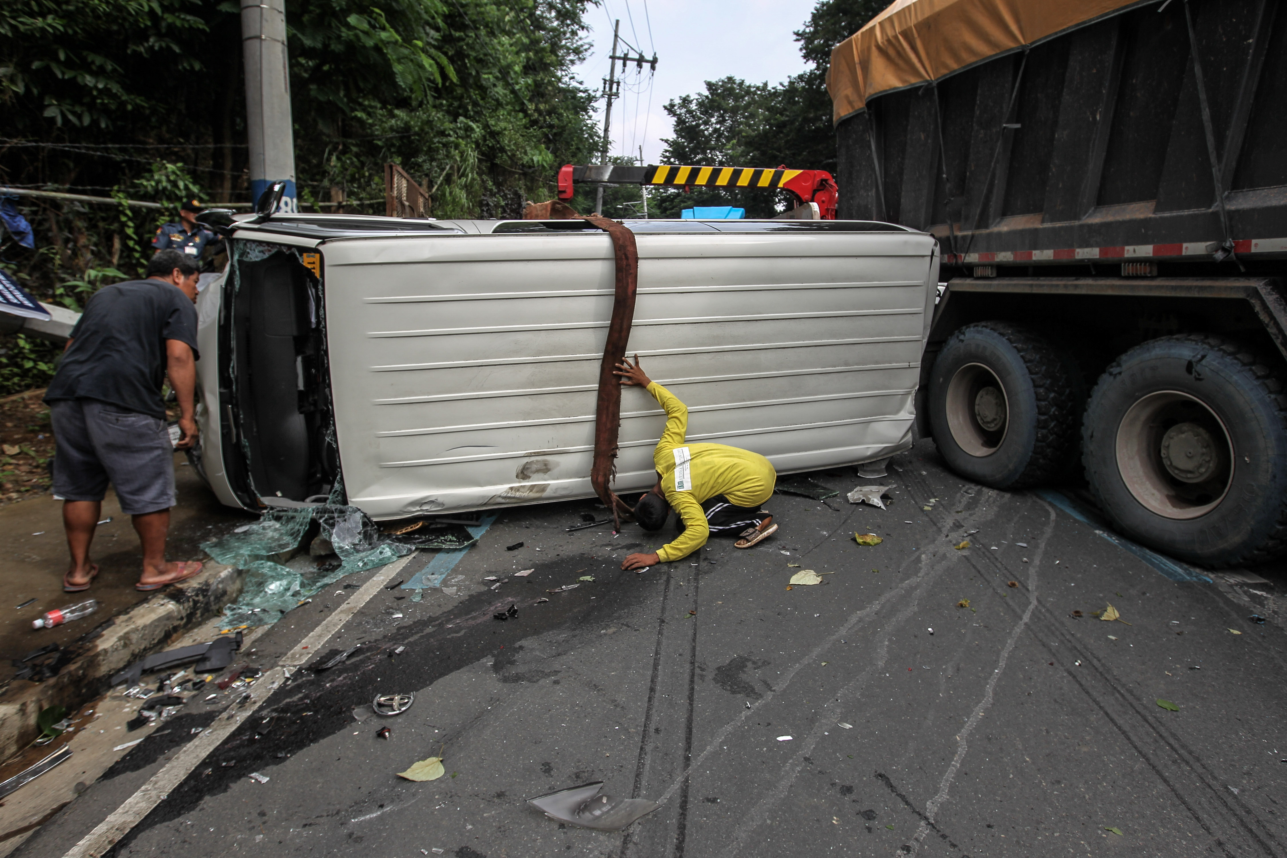 A man looks under one of the vans they are trying to move away from the site of a 9-vehicle accident along Sumulong Highway in Antipolo City, on August 22, 2018. Jonathan Cellona, ABS-CBN News/file